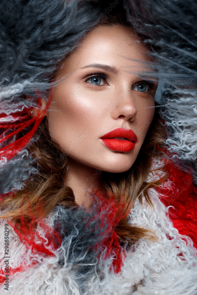 Beautiful woman with classic holiday make-up, red lips, curls in a multi-colored llama coat. Beauty face. Beautiful woman with classic holiday make-up, red lips, curls in a multi-colored llama coat. Beauty face.