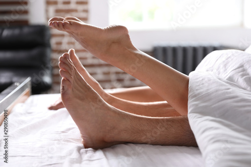 Passionate young couple having sex on bed at home, closeup of legs