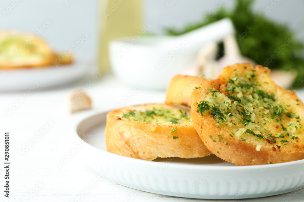 Slices of toasted bread with garlic and herbs on white wooden table, closeup