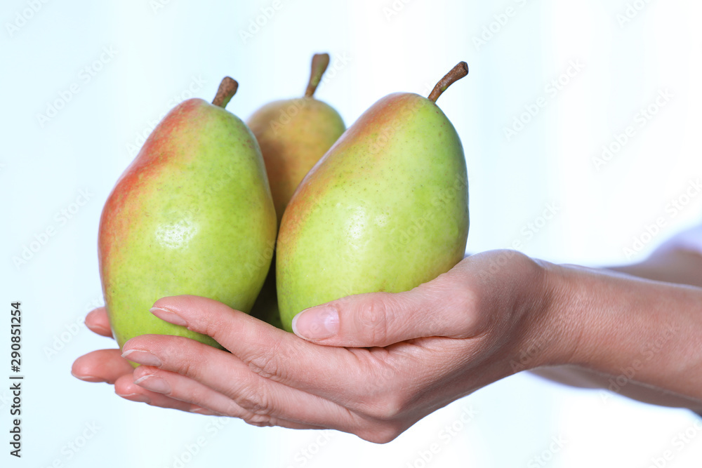 Woman holding fresh ripe pears against light background, closeup Woman holding fresh ripe pears against light background, closeup