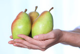 Woman holding fresh ripe pears against light background, closeup