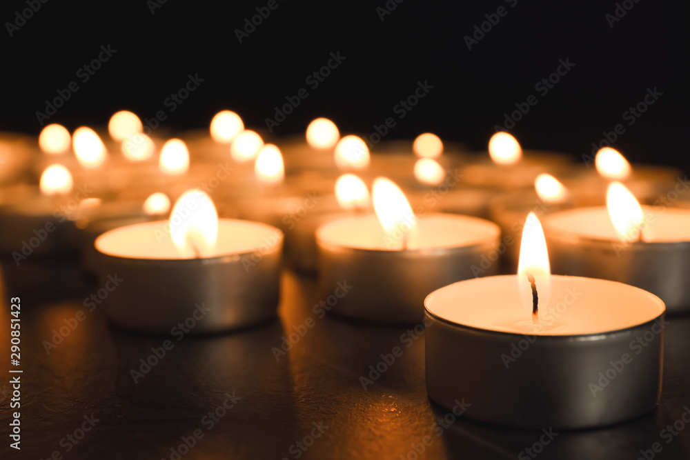 Burning candles on table in darkness, closeup. Funeral symbol Burning candles on table in darkness, closeup. Funeral symbol