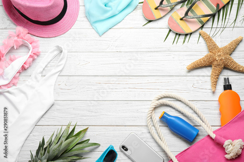 Flat lay composition with beach accessories on white wooden background, space for text