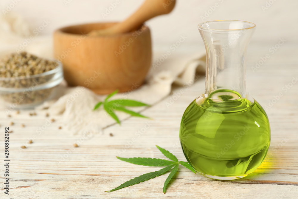 Bottle of hemp oil on white wooden table. Space for text Bottle of hemp oil on white wooden table. Space for text