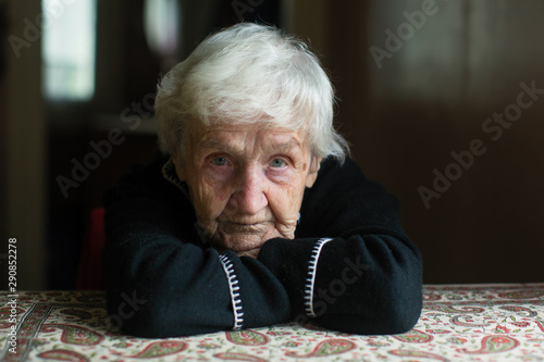 Portrait of a lonely gray-haired old woman in his home.