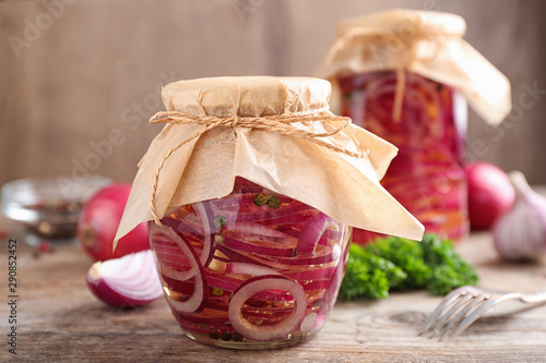 Jars of pickled onions on wooden table