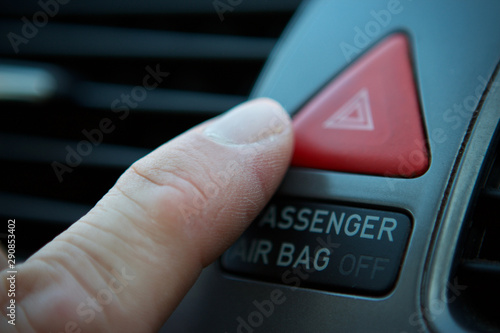 mans finger pressing the hazard lights swith in a car photo