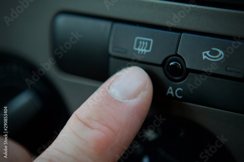 mans finger close up, pressing the ac button in a car