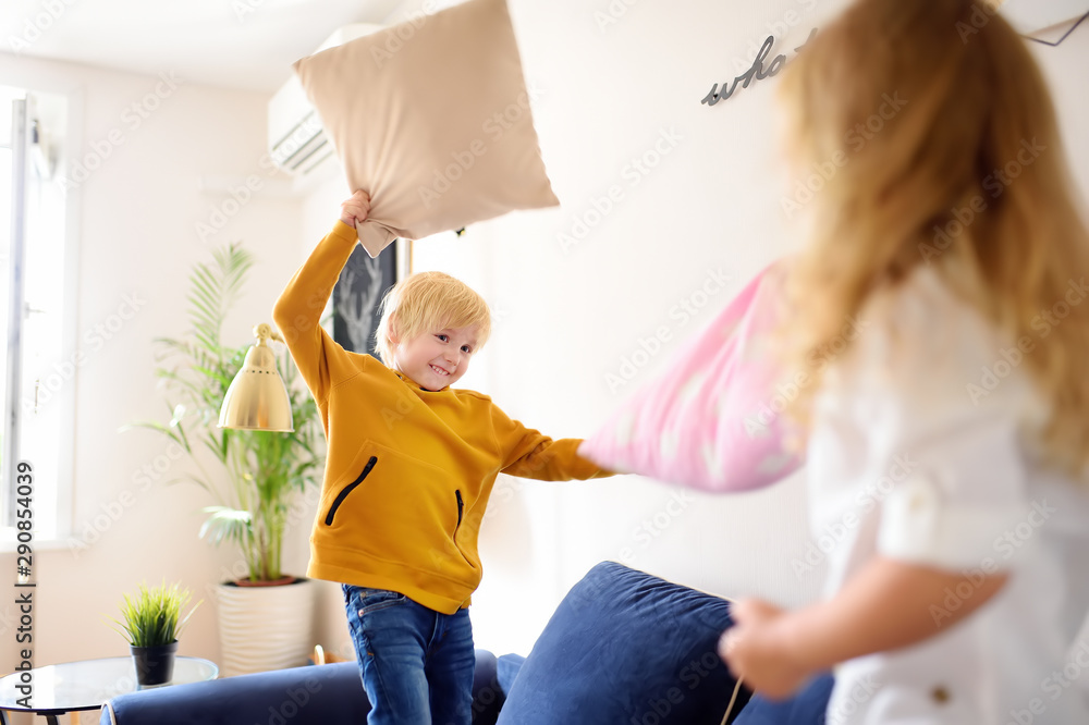 Fototapeta premium Pillow fight. Brother and sister play together. Active games for siblings at home.