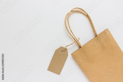 Blank mockup kraft paper present shopping bag with label tag on white background. Photo with copy blank space on the left of image.