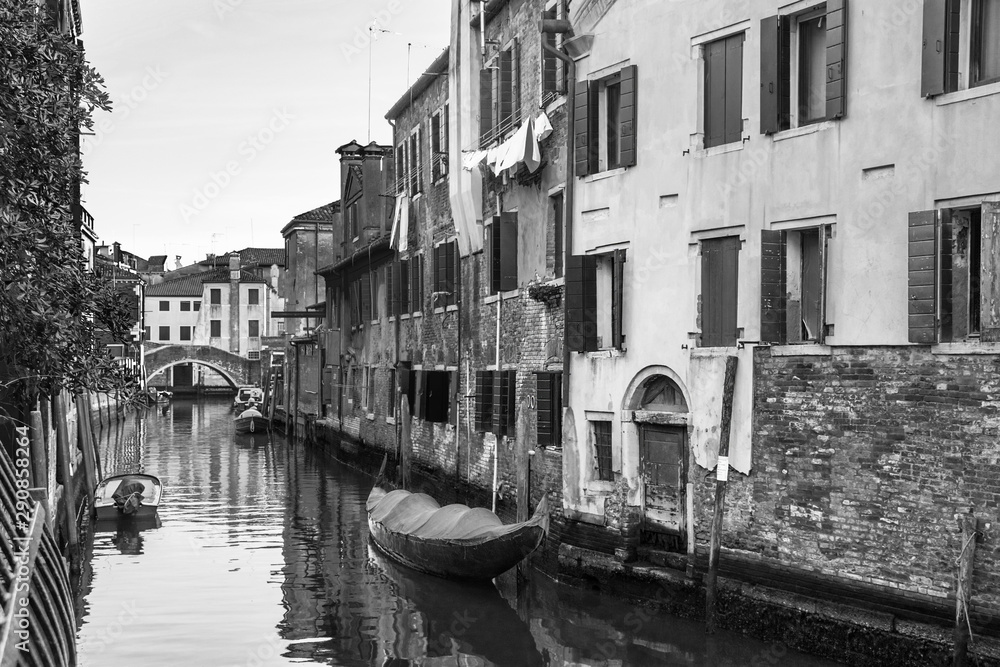 Fototapeta premium Narrow canal in Venice, Italy, with boats and historic houses, in a beautiful sunny day.