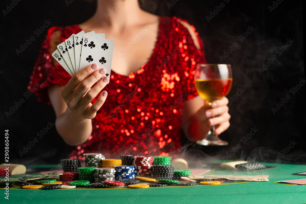 Young girl plays poker in a casino. Focus on playing cards in focus.