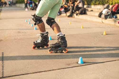 Εκτύπωση καμβά Close-up view of the rollers of a caucasian man, doing rollerblading, inline skating, performing on a slalom course on asphalt surface