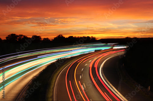 Traffic with motion cars with luminous speed lines and evening sky with beautiful sunset sky, natural landscape