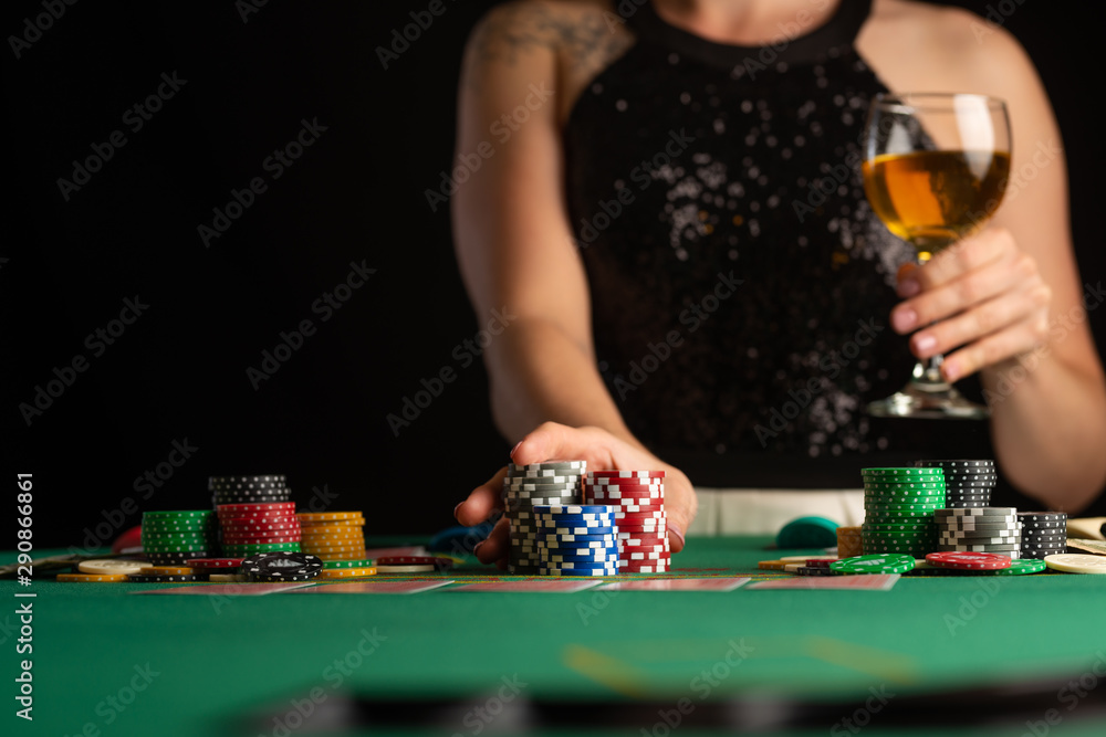 a girl in an evening dress plays poker by raising bets with chips in a casino. focus on chips in focus a girl in an evening dress plays poker by raising bets with chips in a casino. focus on chips in focus