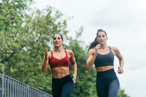runners twins jogging over a bridge with a city landscape