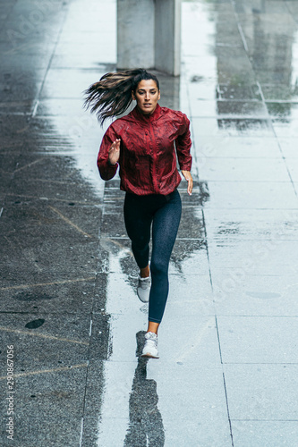 runner girl under the rain along the city