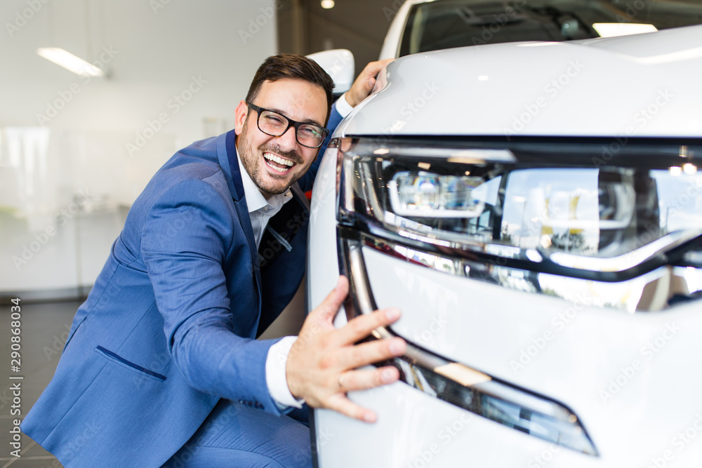 Young handsome man choosing a new car at car showroom. Young handsome man choosing a new car at car showroom.