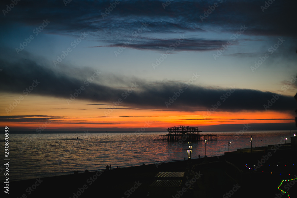 sunset on beach overlooking burned down pier sunset on beach overlooking burned down pier