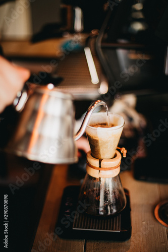 Barista pouring coffee into glass chemex