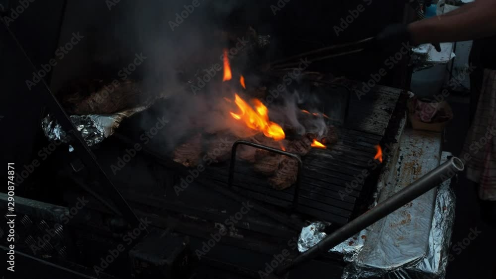 Black angus cow steak grilled on a barbecue. Fire and smoke. Cooks hand moving. Black angus cow steak grilled on a barbecue. Fire and smoke. Cooks hand moving.