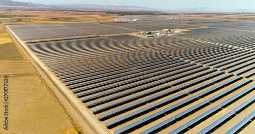 Solar panels in a solar farm in Spain. There is the reflection of the sun in the the panels which produce renewable energy, solar energy - aerial view with a drone - environment and renewable energy c