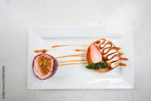 Fruit pie on white ceramic plate. Strawberry, blueburry, passion fruit assorted on crispy baked pastry cup with creamy on top photo