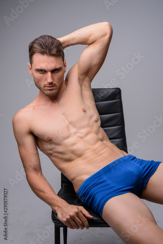 Portrait of handsome muscular man shirtless sitting on chair