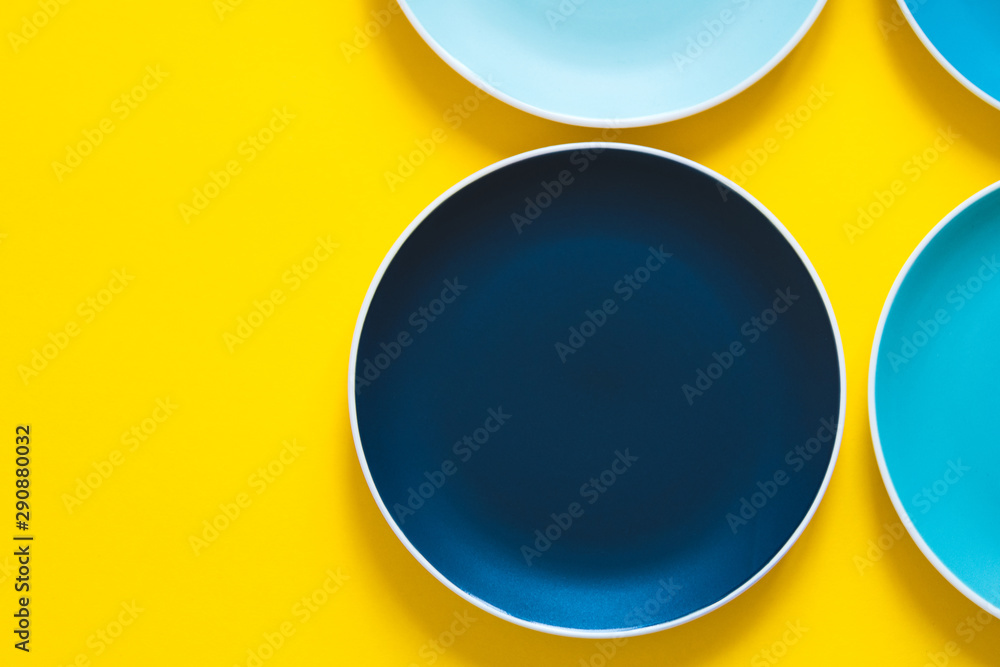 Colorful pastel blue ceramic plates isolated on yellow background. Top view. Colorful pastel blue ceramic plates isolated on yellow background. Top view.