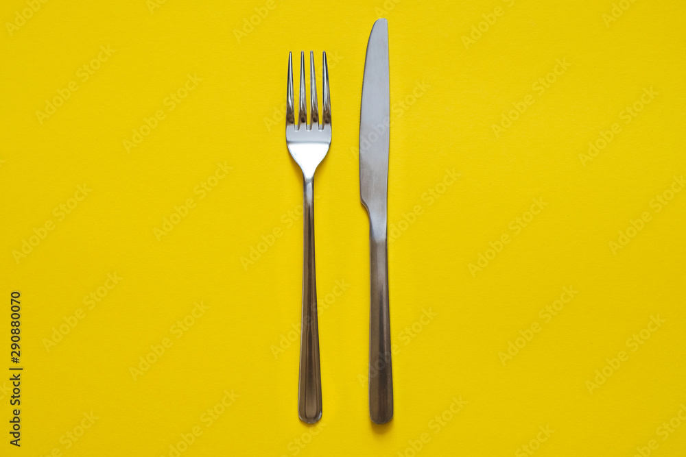 Fork and knife isolated on yellow background. Top view. Fork and knife isolated on yellow background. Top view.