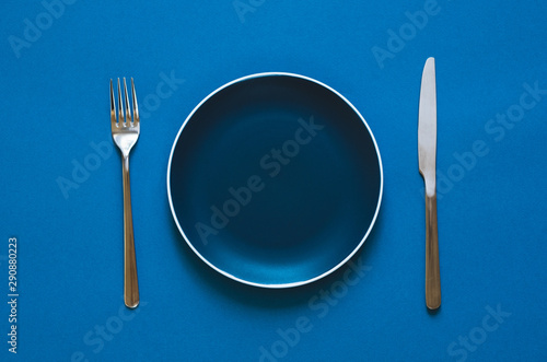 Plate fork and knife isolated on blue background. 