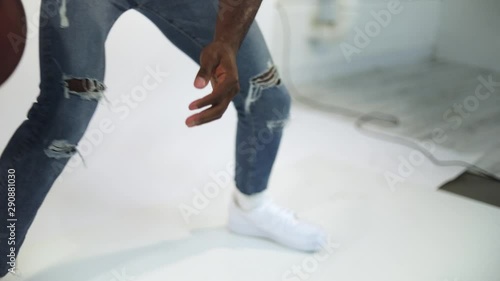 Slow Motion shot of an African American dribbling a basketball. Shot in a studio with a white background. The man is wearing a non-brand inspiring shirt with the message 