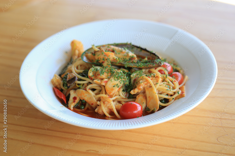 Seafood aaspicy spagetti with scallop, squid, shrimp and basil in white plate.  The famous Italian dish used long slim noodle.