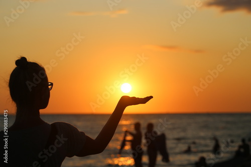 Photo of a silhouette of a girl at sunset against the background of the sun