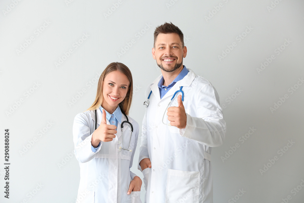 Doctors showing thumb-up on light background Doctors showing thumb-up on light background