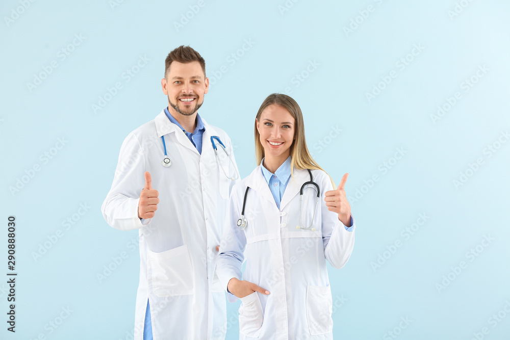 Male and female doctors showing thumb-up on light color background Male and female doctors showing thumb-up on light color background