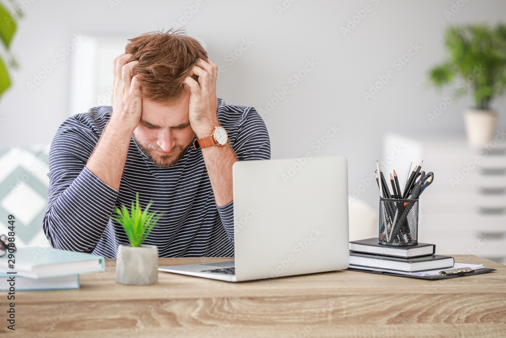 Stressed young man at table in office Stressed young man at table in office