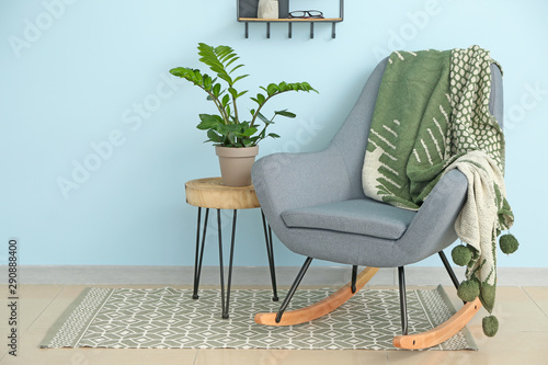 Table with houseplant and armchair near color wall