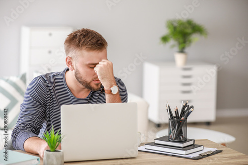 Stressed young man at table...