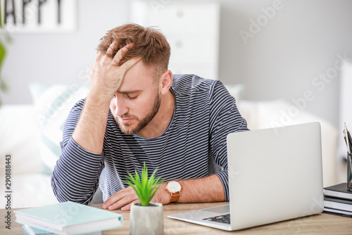 Stressed young man at table...