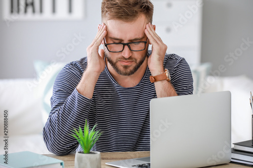 Stressed young man at table...