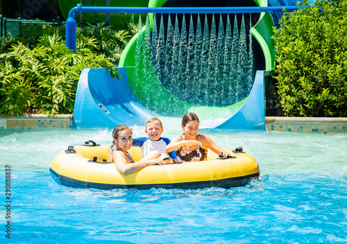Family having fun together a water park. Riding on an inflatable tube together on a water slide.  photo