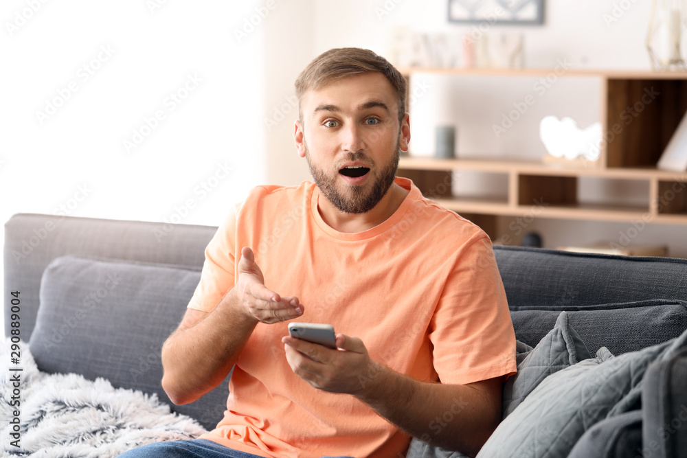 Surprised young man with mobile phone at home Surprised young man with mobile phone at home