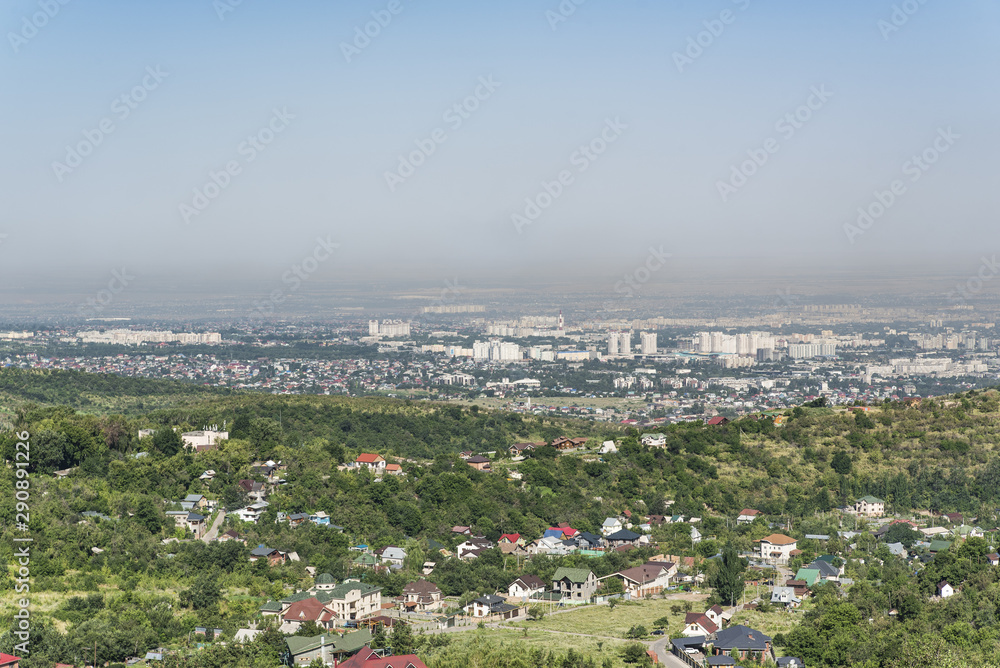 View from a high mountain on the city of Almaty. In the foreground in slope country houses and villas.