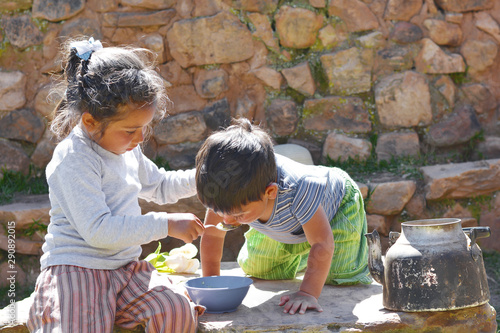 Foto Little latin children sitting on the big stone and eating from a bowl