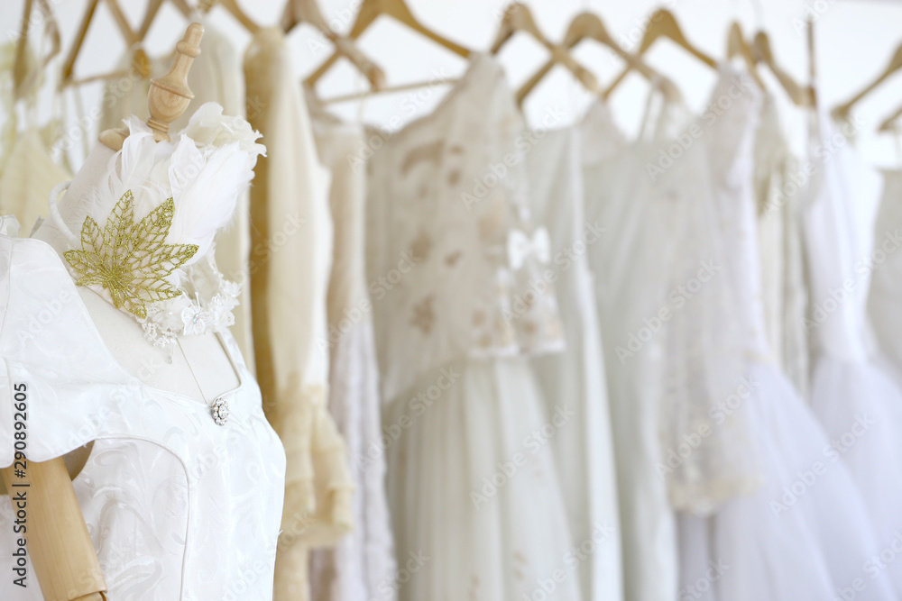 Wedding white gown for bride hanged in costume showroom for marriage or wedding reception. White delicated lace on long dress for promp or party Wedding white gown for bride hanged in costume showroom for marriage or wedding reception. White delicated lace on long dress for promp or party