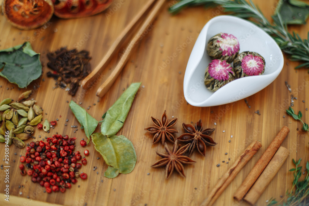 Chinese Oolong jasmine tea Moli Yu Lun Tao in a white bowl. On a wooden board scattered a lot of ingredients for tea. Shallow depth of field. Chinese Oolong jasmine tea Moli Yu Lun Tao in a white bowl. On a wooden board scattered a lot of ingredients for tea. Shallow depth of field.