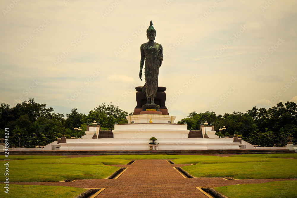 Standing buddha for worship in Phutthamonthon Park with sunset sky and reflective light,beautiful background