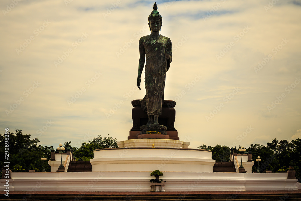 Standing buddha for worship in Phutthamonthon Park with sunset sky and reflective light,beautiful background Standing buddha for worship in Phutthamonthon Park with sunset sky and reflective light,beautiful background