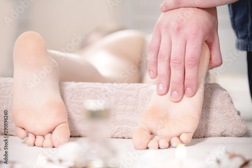 Close-up Relaxing foot massage at the spa. Male hands knead the female foot. Body care concept © yanik88